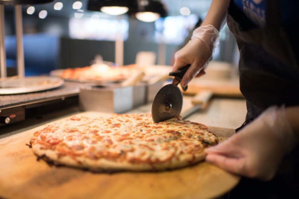 A fresh baked pizza being cut.